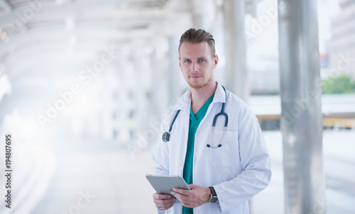 medical doctor professional team talked consult. Two young doctor Caucasian and Asian standing in hospital holding laptop and folder city building background.