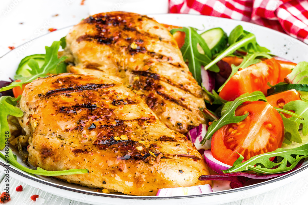 Grilled chicken breast. Fried chicken fillet and fresh vegetable salad of tomatoes, cucumbers and arugula leaves. Chicken meat salad. Healthy food. White background Grilled chicken breast. Fried chicken fillet and fresh vegetable salad of tomatoes, cucumbers and arugula leaves. Chicken meat salad. Healthy food. White background