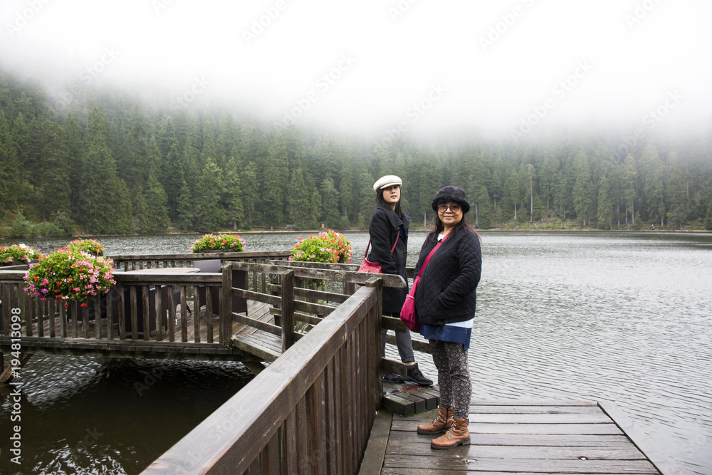 Asain thai women mother and daughter travel and posing at Mummelsee lake while raining in Black Forest or Schwarzwald at Baden-wurttemberg of Stuttgart, Germany