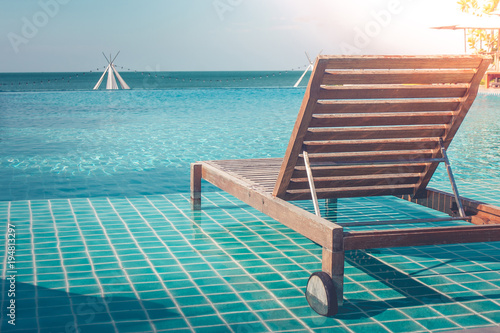 Vacation and Holiday Concept : Close up wooden daybed in swimming pool for sunbathing and resting in summer trip seasonal.
