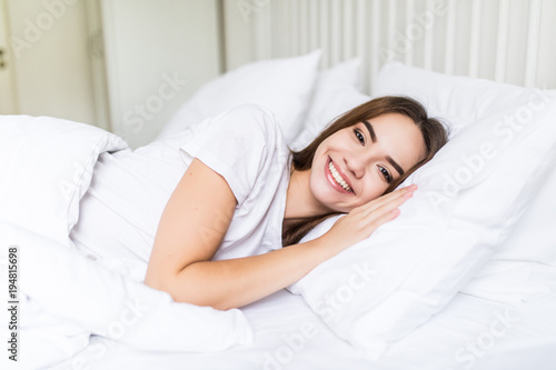 Young pleased sleeping on the side young woman smiling softly in bed