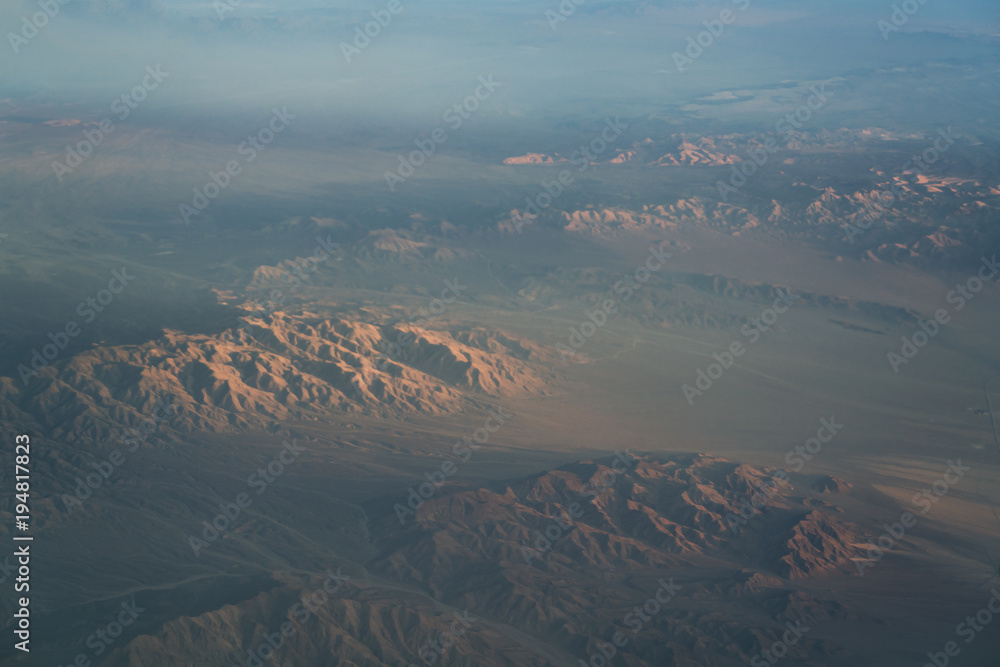 view from plane during flight over California mountains in sunset