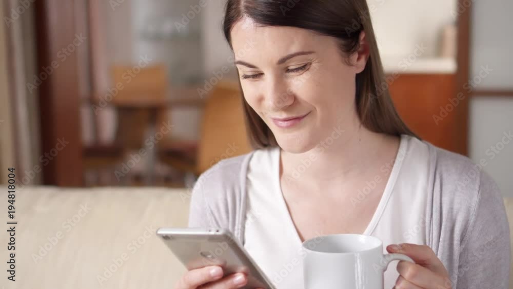 Businesswoman working on mobile phone at home drinking coffee from cup. Young female professional checking email in the morning, browsing, reading news. Remote freelance work. Home-office concept Businesswoman working on mobile phone at home drinking coffee from cup. Young female professional checking email in the morning, browsing, reading news. Remote freelance work. Home-office concept