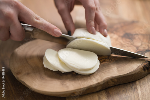 Εκτύπωση καμβά female teen hand slicing mozzarella cheese with knife on wooden board