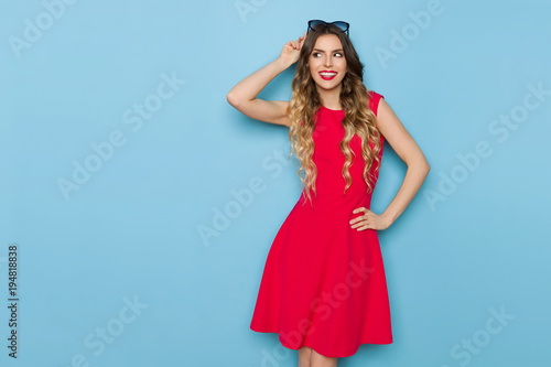 Beautiful Fashion Model In Red Dress Is Smiling And Looking Away