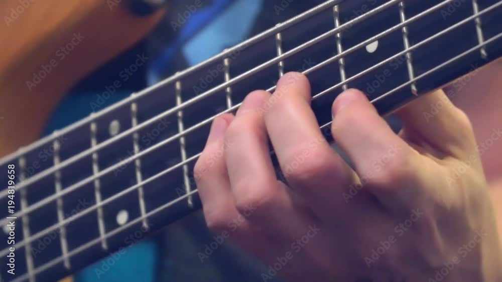 Fingers of the guitarist's bass on the fretboard close-up. Plays bass guitar. Selective focus Fingers of the guitarist's bass on the fretboard close-up. Plays bass guitar. Selective focus