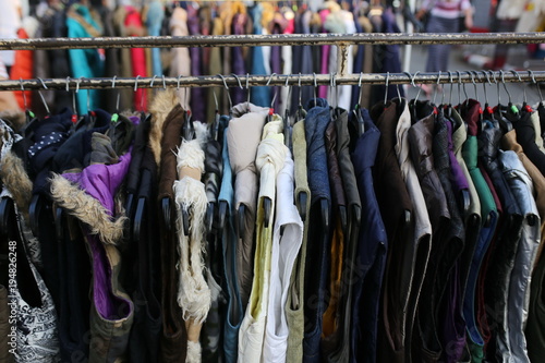 Variety of colored winter and autumn clothes on metal hangers in the wardrobe of a cinema on back stage, theater or exhibition. Top view of a large number of different clothes