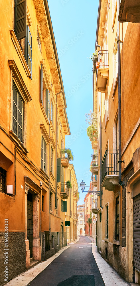 Naklejka premium VERONA, ITALY - AUGUST 17, 2017: Narrow street of Verona high vibrant building facades.