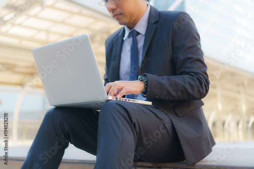 Businessman sitting on the footsteps with laptop