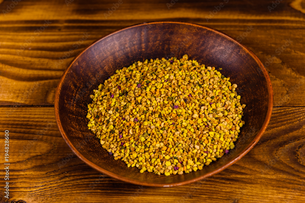Ceramic plate with bee pollen on wooden table