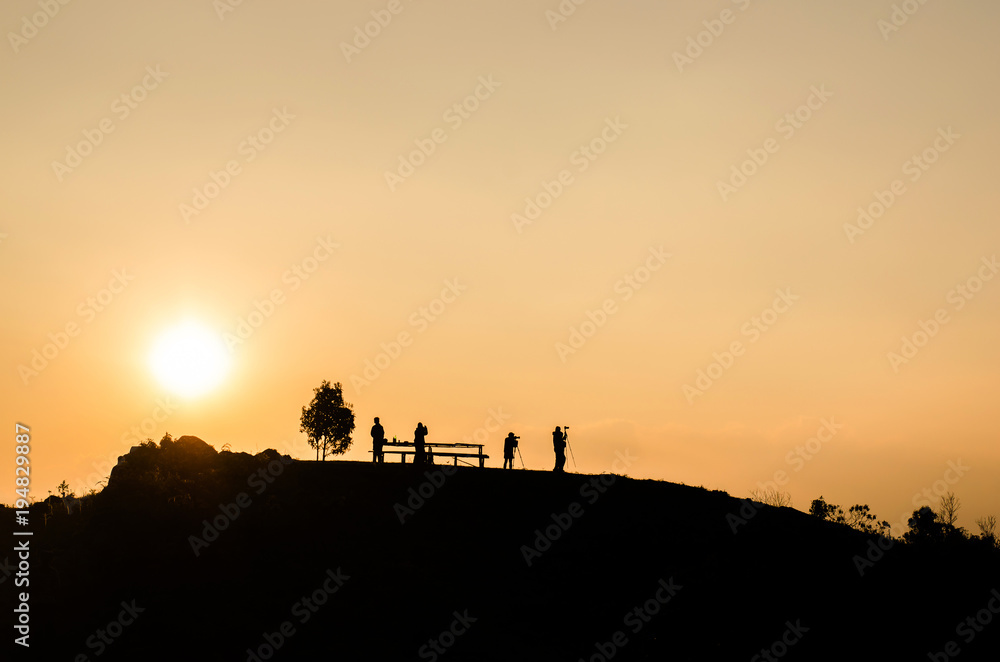 silhouette of people on the top of mountain with sun set background