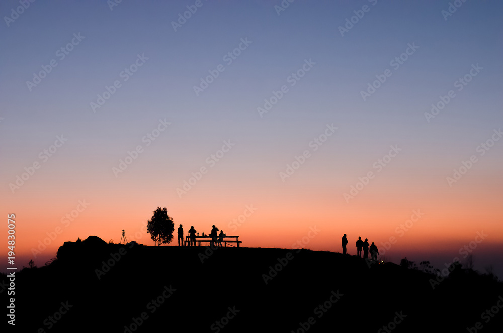 silhouette of people on the top of mountain with sun set background