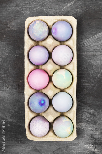 Multicolored eggs for Easter in container for eggs on black background. Top view. Food background