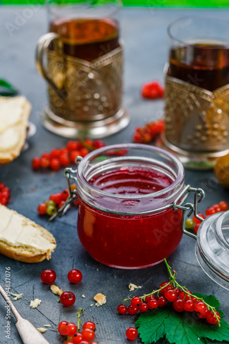 Red currants and jar of jam in garden