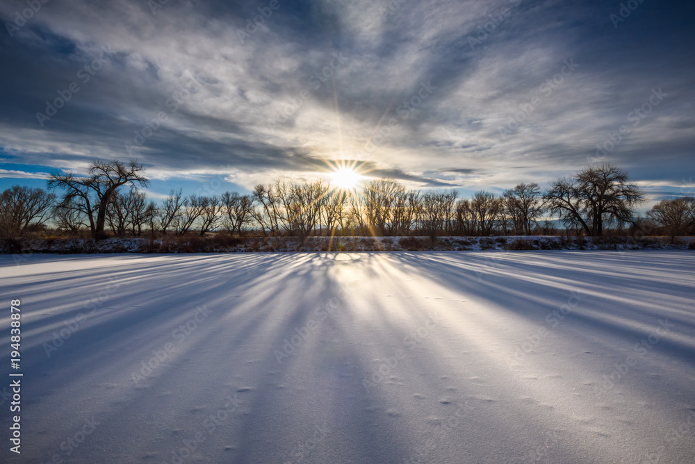 Long shadows over the frozen pond at sunset Long shadows over the frozen pond at sunset