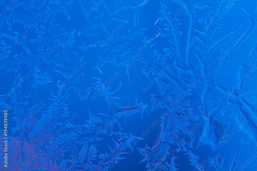 Frosty patterns on window glass on blue background Frosty patterns on window glass on blue background