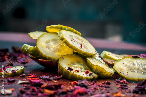 Close up of Ayurvedic face pack's ingredients i.e  cucumber and Aloe Vera gel with rose petals on a wooden surface in dark Gothic colors.It helps in brighting the skin tone. photo