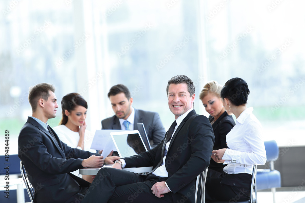businessman and his business team with financial documents sitting at a Desk in the lobby of the Bank. businessman and his business team with financial documents sitting at a Desk in the lobby of the Bank.