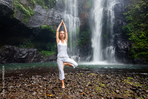 Woman practices yoga near Sekumpul waterfall in Bali, Indonesia