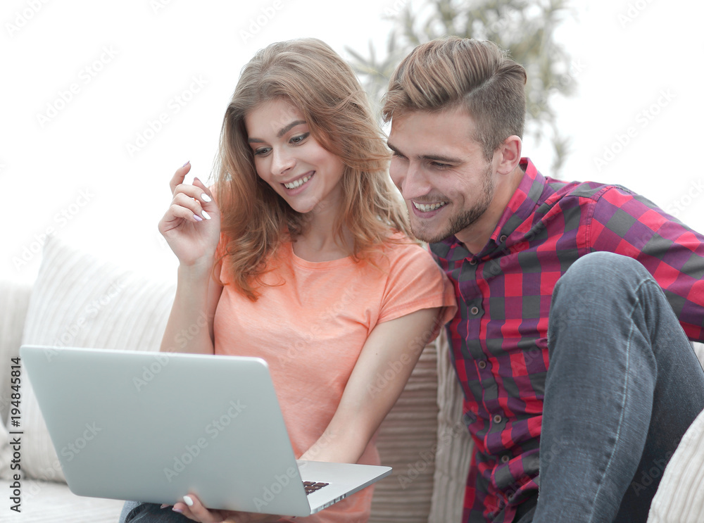 young man with his girlfriend watching a TV show on the laptop sitting in the living room