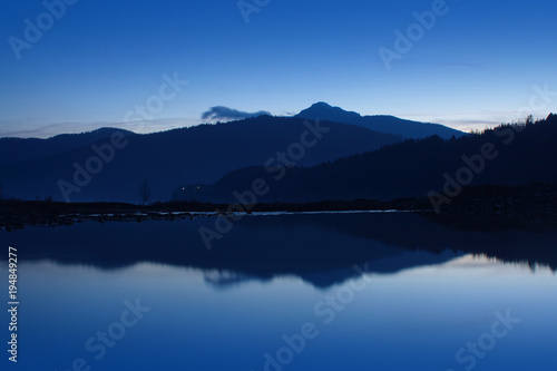 lake and mountain at twilight or blue hour. landscape in Hangu, Ceahlau in background. Romania