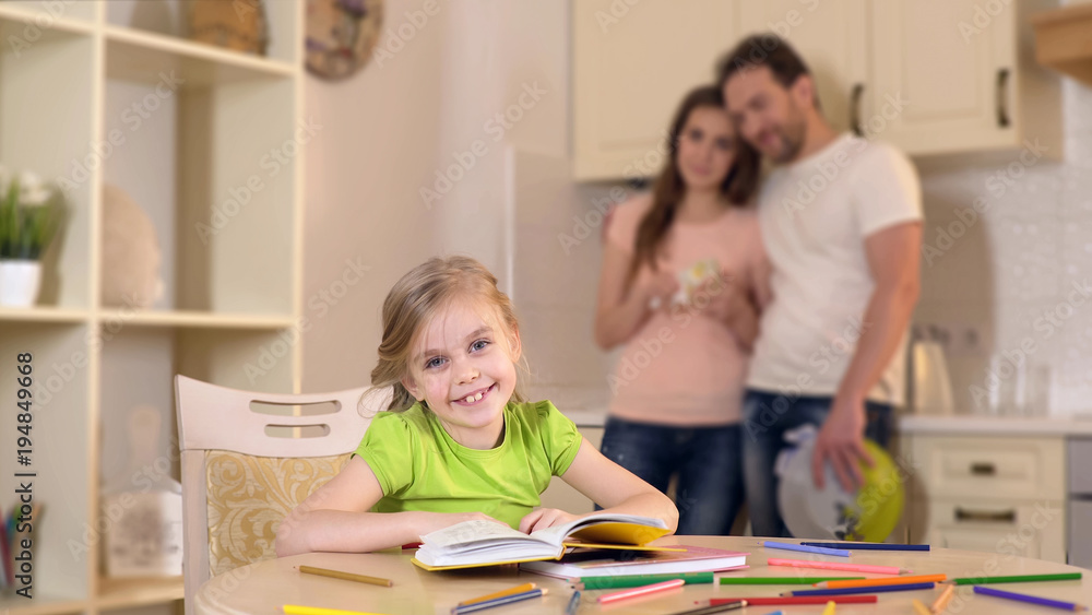 Happy girl smiling for camera, loving parents hugging and looking at daughter Happy girl smiling for camera, loving parents hugging and looking at daughter