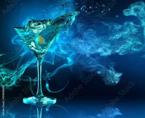 Obraz na plátně martini cocktail splashing in dark blue smoky background