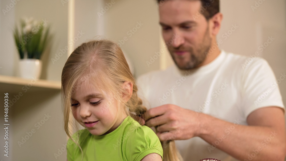 Happy single father braiding daughter's hair, taking care of beloved little girl Happy single father braiding daughter's hair, taking care of beloved little girl