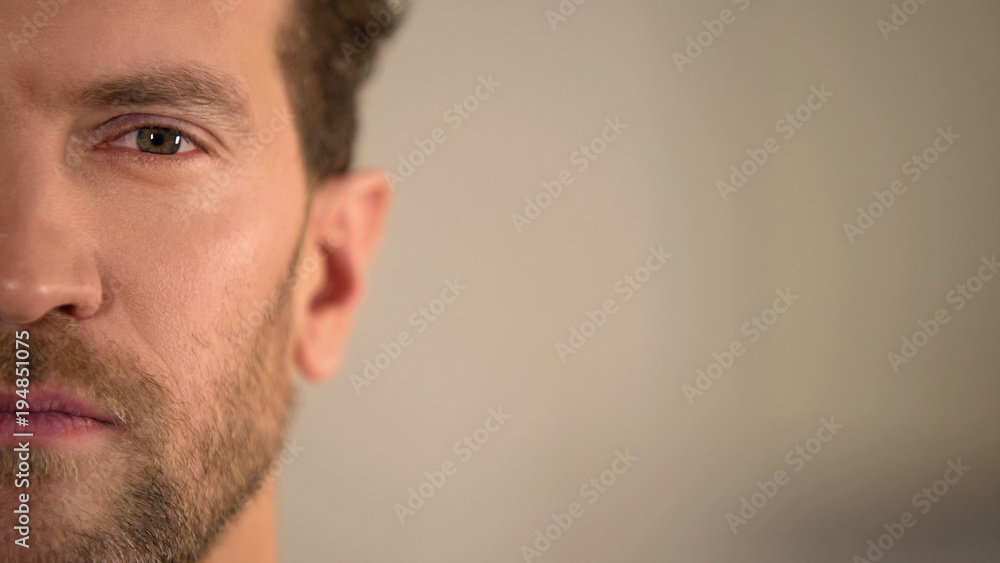 Fototapeta premium Young male half face looking into camera, average man opinion poll, statistics