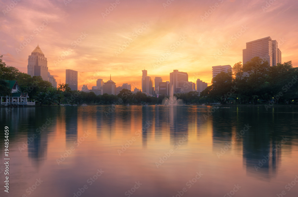 cityscapes of modern city and skyline at golden hour before the night with water reflection from the public park.