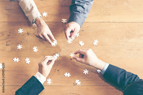Businessman team work holding two jigsaw connecting couple puzzle piece for matching to goals target, success and start up new project in office, top view.  Business Concept. photo