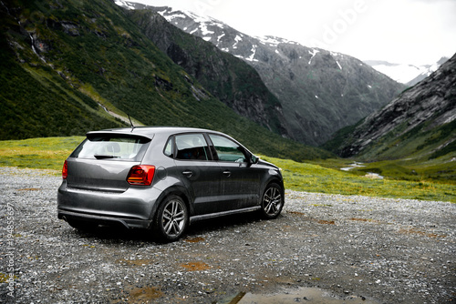 Grey modern car parking at a viewpoint in the mountains of Norway facing towards the green valley.