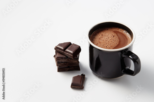 Black mug with hot chocolate served with chunks of dark chocolate