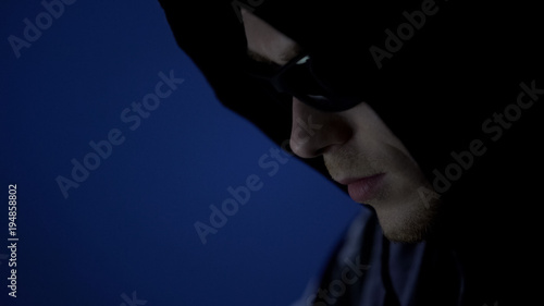 Male thief in hoodie and sunglasses, preparation before offense, face close up