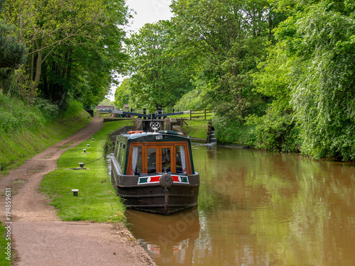Fototapeta Moored narrowboat between two canal locks  on the Shropshire Union Canal near Audlem in Cheshire, England