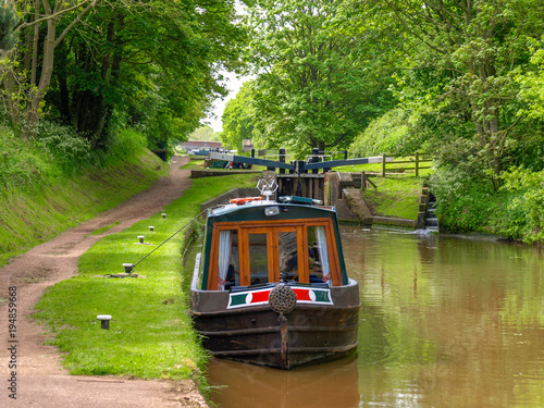 Moored narrowboat between two canal locks  on the Shropshire Union Canal near Audlem in Cheshire, England.