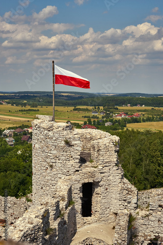 Polska flaga narodowa łopocząca na wieży obronnej zamku w Ogrodziencu, w tle piękny letni krajobraz okolicy