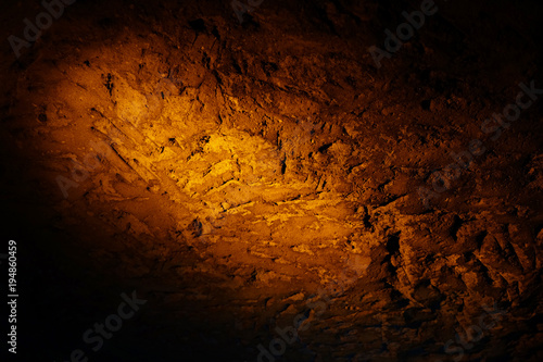 Natural texture created on the wall in the underground cave in Mazi underground city, Sehri, Turkey, enlightened by orange color spotlight