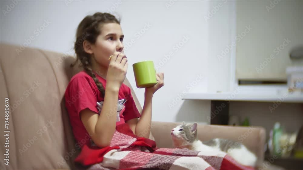 girl teenager eating a sandwich drinking tea and watching tv. girl child eating a sandwich cat trying to take indoors food girl teenager eating a sandwich drinking tea and watching tv. girl child eating a sandwich cat trying to take indoors food