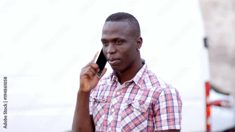 Attractive black american young man talking by phone in the city- slow motion Attractive black american young man talking by phone in the city- slow motion
