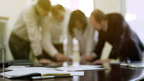 Company colleagues discussing report papers at business meeting, cooperation