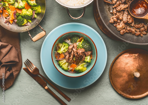 Healthy balanced nutrition dish with beef meat, steamed vegetables and rice on table background with plate and cutlery, top view