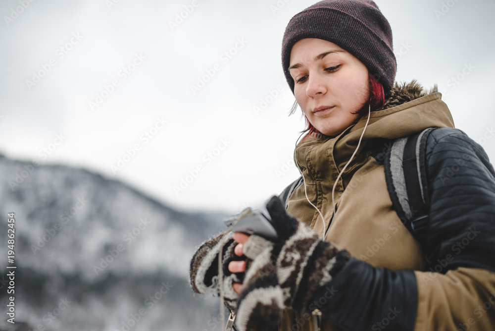 Smiling girl listening the music in winter mountains