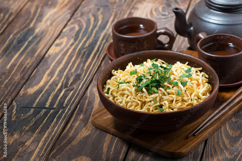 bowl with traditional Chinese noodles and tea on wooden background