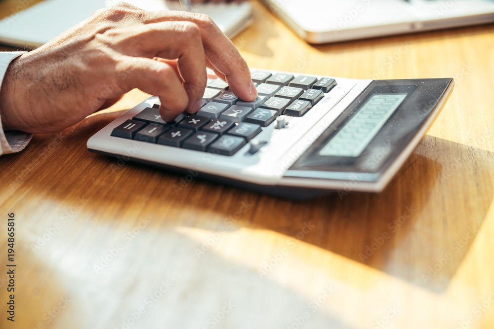 An asian businessman press the calculator button on his working desk by close-up his right hand, Business concept. An asian businessman press the calculator button on his working desk by close-up his right hand, Business concept.