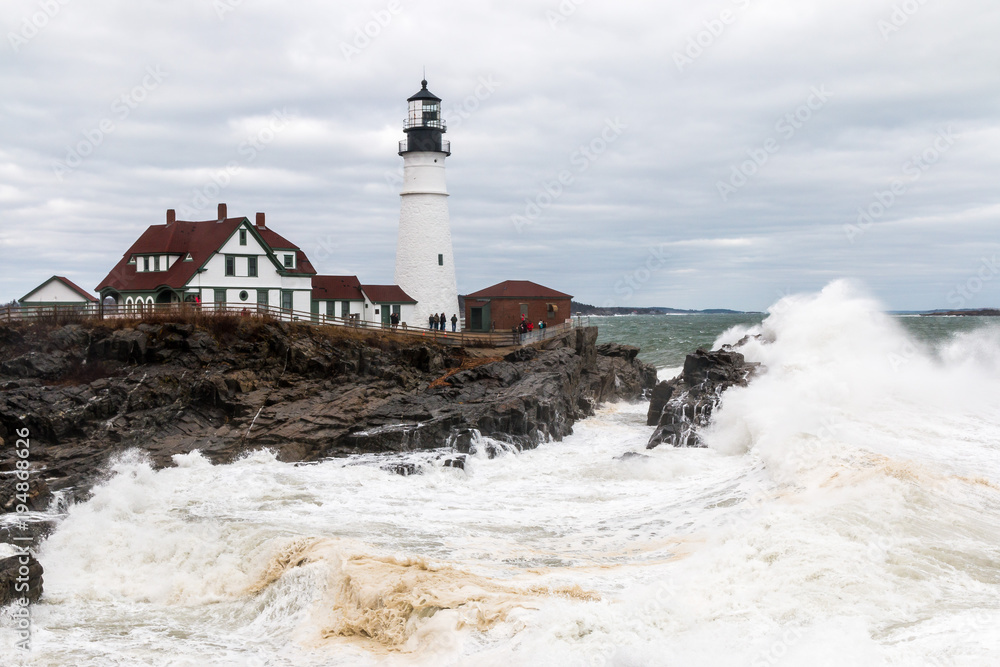 Portland Head Lighthouse during a storm with large waves. 