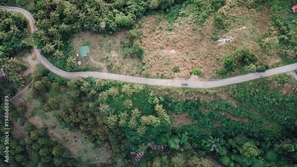 Aerial shooting from flying drone of a moving car on a way in Asia ...