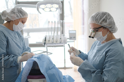 Doctor with an assistant in the surgical dental surgery in the clinic photo