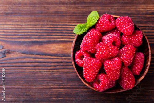 Raspberries in bowl on wooden table. Top view. Copy space.