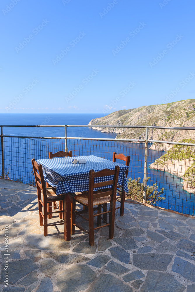 Fototapeta premium Tables with chairs on terrace of coastal restaurant in Porto Schiza on Zakynthos island. Greece.